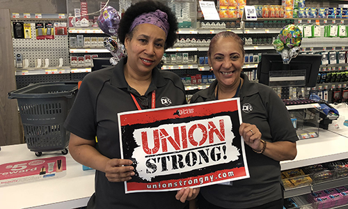 two members standing side by side holding a union strong sign