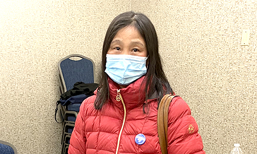 Member posing in a picture in a red jacket and face mask