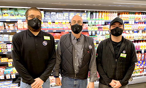 three members standing side by side in the frozen food section