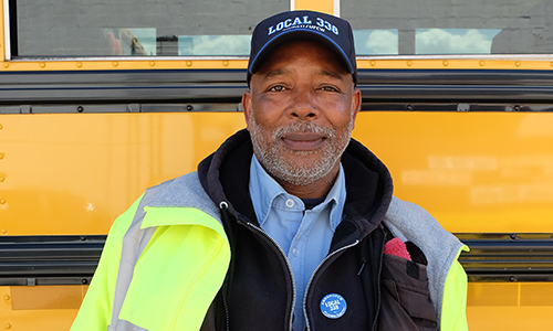 Member standing smiling next to a bus